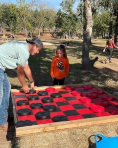 Dad and daughter playing giant checkers at Walnut Woods. 