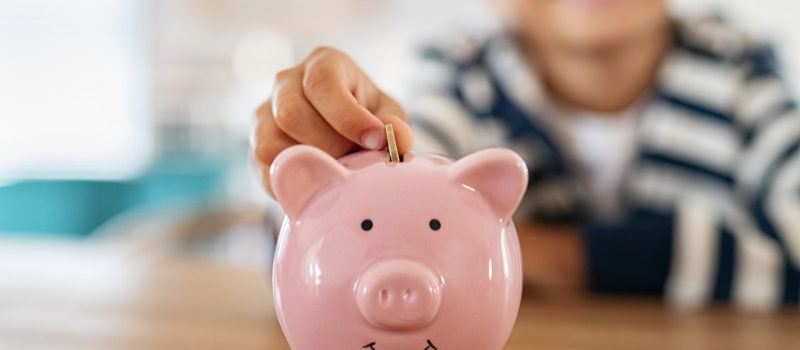 kid saving money by collecting money and putting it in a piggy bank