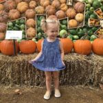 little girl poses in front of pumpkins at Pumpkinville, Myriad Gardens' annual pumpkin patch. 