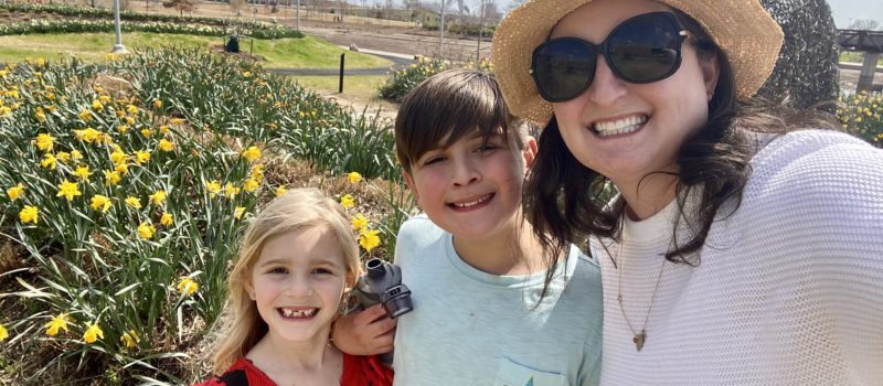 mom, son, and daughter posing for a picture in a garden