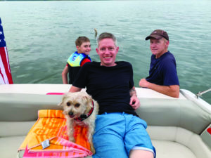The author's son, husband, father and dog sitting on their boat in Lake Tenkiller