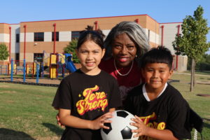 OKCPS Superintendent Dr. Jamie Polk with two elementary students at a soccer field ribbon cutting
