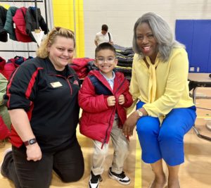 OKCPS Superintendent Dr. Jamie Polk at a Coat a Kid event with a student and a volunteer